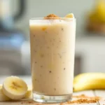 A glass of creamy banana bariatric shake garnished with cinnamon and banana slices.